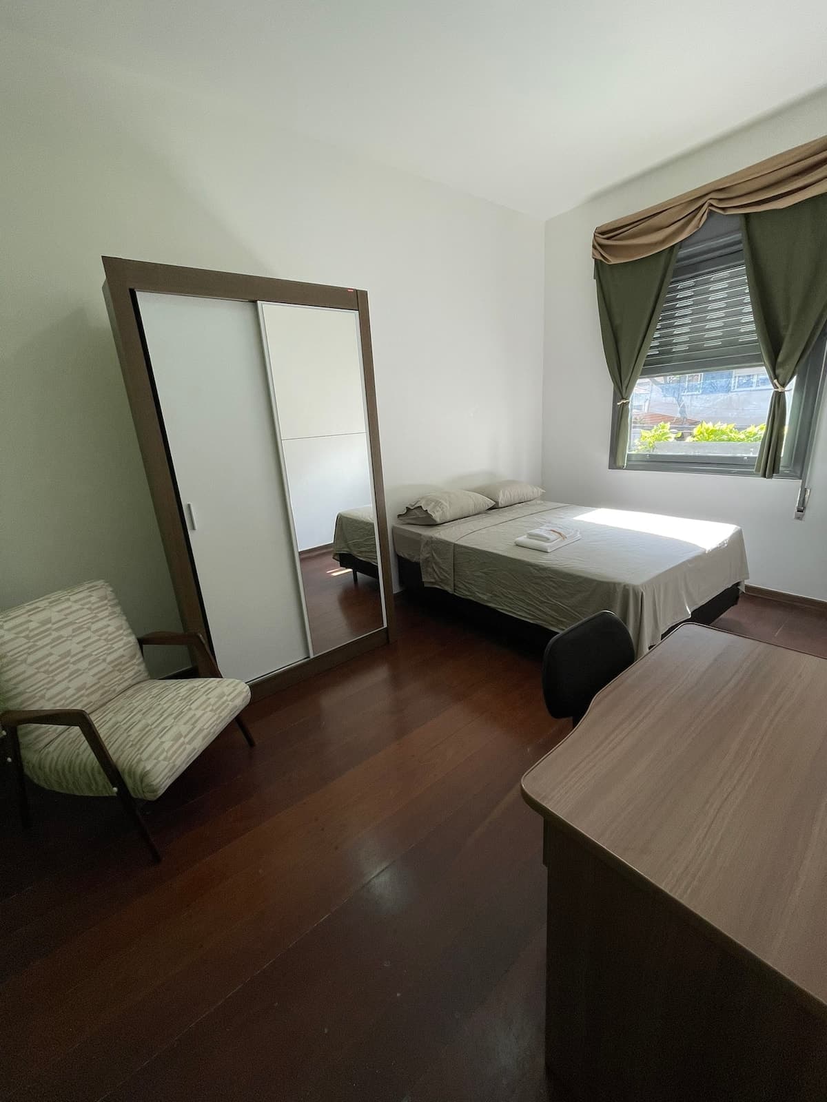 Quarto 12 com cama de casal, guarda-roupa e poltrona
